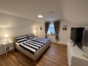 Schlafzimmer mit einem Bett und einem Flachbild-TV in der Unterkunft Ferienwohnung Deichblick in Emden