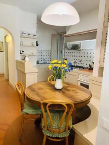 kuchnia z drewnianym stołem z krzesłami i wazonem kwiatów w obiekcie Appartamenti sul mare Villa il Fortullino w mieście Case Fortullino