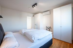um quarto com uma cama branca e um armário branco em Penthouse I Dachterrasse I Tiefgaragenstellplatz I nahe Bhf, JoHo, Brita-Arena em Wiesbaden