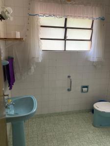 een badkamer met een blauwe wastafel en een toilet bij Aconchegante casa nas montanhas de Serra Negra in Serra Negra