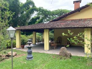 een geel huis met een veranda met een lamp in de tuin bij Aconchegante casa nas montanhas de Serra Negra in Serra Negra