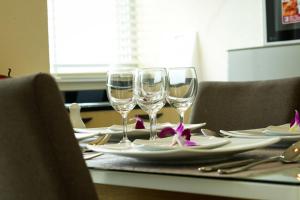 a table with three wine glasses and plates on it at Patt Serviced Apartments in Chon Buri