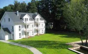 a large white house on a green lawn at Louisenhof Ferienapartments und Wellness in Burg