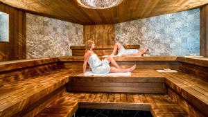 Duas mulheres estão sentadas numa sauna. em Natuurhuisje Bergvliet - Nature, Golf & Wellness em Oosterhout