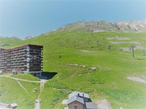 un edificio su una collina erbosa accanto a una montagna di Studio cosy à Tignes, au pied des pistes et commerces - FR-1-411-481 a Tignes