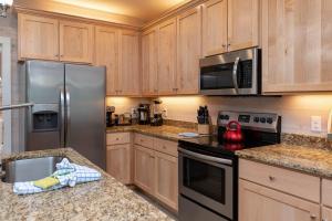een keuken met houten kasten en een roestvrijstalen koelkast bij Jetty Life 473 home in Gulf Shores