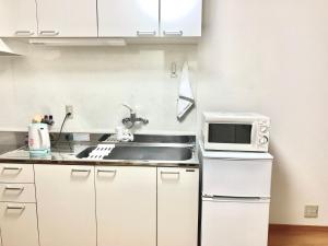 uma cozinha com um lavatório e um micro-ondas em 花楓舎-Sakura & Maple Guest House-ゲストハウス em Quioto