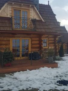 a log house with snow in front of it at Góralskie przytulne Domki u Kantora in Poronin