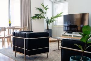 a living room with two chairs and a flat screen tv at Cottesloe Beach View Apartments #11 in Perth