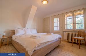 Chalet Pradella by Arosa Holiday في أروسا: غرفة نوم بسرير وملاءات بيضاء ونافذة