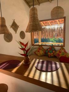 Habitación con una mesa con almohadas y una ventana. en Casa Jandaia Trancoso - apartamento superior, en Trancoso