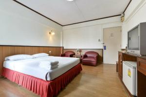 a hotel room with a bed and a flat screen tv at Nice Palace Hotel in Bangkok