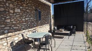 eine Terrasse mit einem Tisch, Stühlen und einer Steinmauer in der Unterkunft studio en pierres traditionnelle in Essaouira