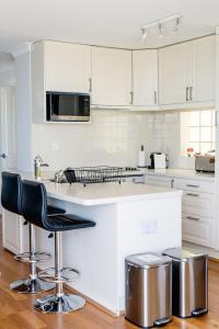 una cocina con armarios blancos y una barra con taburetes en Cottesloe Beach View Apartments #11 en Perth