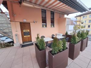 eine Terrasse mit Tischen und Topfpflanzen auf einem Gebäude in der Unterkunft Appartamento Al Ponte adiacente al parco, vicino all'ospedale e centro in Trient