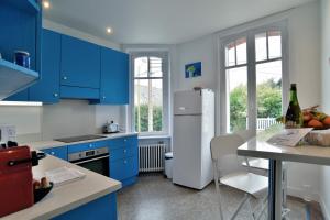 a kitchen with blue cabinets and a white refrigerator at Ile Celée - Maison de caractère proche plage in Dinard +9 photos