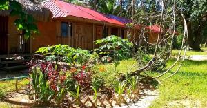 a garden with flowers in front of a house at Arkadia Beach Resort Underground River in Sabang