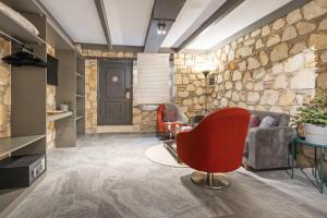 a living room with a stone wall and a red chair at Charming Flat near Hadrians Gate in Antalya