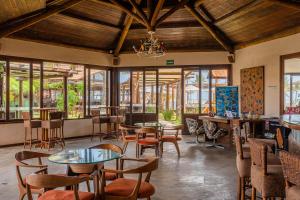 un restaurante con mesas, sillas y ventanas en Aruanã Eco Praia Hotel, en Aracaju