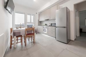 a white kitchen with a table and a refrigerator at Realkasa Fiera District Flat in Bologna
