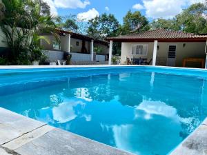 a swimming pool with blue water in front of a house at Chácara das Suculentas in Mairiporã