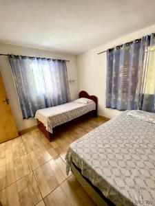 - une chambre avec 2 lits et des rideaux bleus dans l'établissement Chácara das Suculentas, à Mairiporã