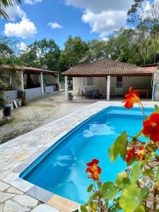 a blue swimming pool in front of a house at Chácara das Suculentas in Mairiporã