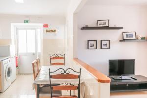 Una cocina con mesa de comedor y televisión. en Amélia Apartment - Peniche Surf Camp, en Peniche