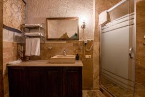 a bathroom with a sink and a mirror and a shower at Hidden Cave Hotel in Göreme