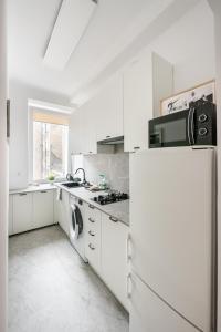 a white kitchen with a refrigerator and a microwave at Chmielna Warsaw City Centre Apartment in Warsaw
