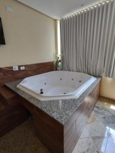 uma grande banheira sentada num balcão na casa de banho em Hotel Pousada Beija Flor em Poços de Caldas