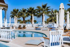 a resort with a pool and chairs and palm trees at Wellness Santa Hotel in Agia Triada