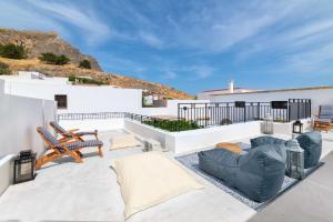 un patio con sillas y un sofá en el techo en Lindos Villa Petra with Acropolis View, en Lindos