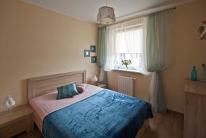 a bedroom with a bed with a blue blanket and a window at Apartamenty Marina House in Bydgoszcz
