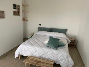 um quarto com uma cama branca e almofadas verdes em B&B Archimede em Scanzano Jonico