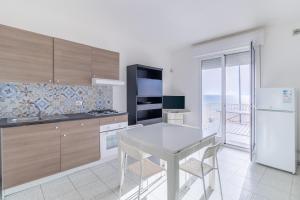 una cucina con tavolo bianco e frigorifero bianco di Appartamento vista mare Scoglitti a Scoglitti