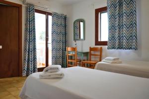 a bedroom with two beds and a table and a window at Apartamentos Vistalmar Mallorca in Cala Figuera