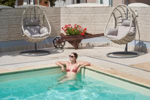 a woman in a swimming pool with two chairs at Hotel Acquario in Rimini