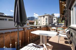 eine Terrasse mit einem Tisch und einem Sonnenschirm auf dem Balkon in der Unterkunft Chalet Schwarzsee by Arosa Holiday in Arosa