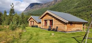 a log cabin in a field with a mountain at Visit Junkerdal in Junkerdal