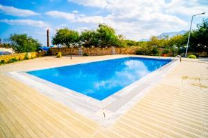una gran piscina en un patio con terraza de madera en Spacious Three-Bedroom Apartment with Sea View A3, en Kyrenia