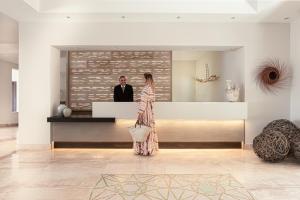 a woman in a dress standing in a lobby with a man at Cala Cuncheddi - VRetreats in Murta Maria