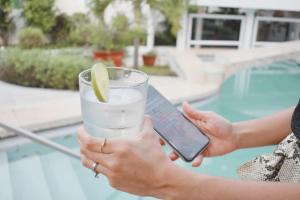 a person holding a cell phone and a glass of water at Saastah Hotel Boutique in Valladolid