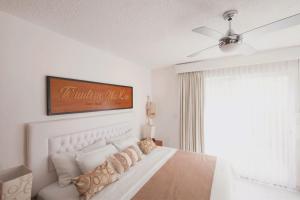 a white bedroom with a bed and a ceiling fan at Saastah Hotel Boutique in Valladolid