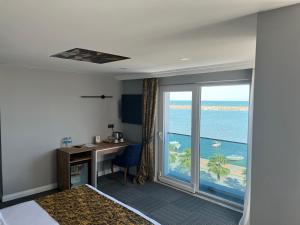 a room with a desk and a view of the ocean at çepnis hotel in Samsun