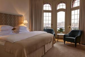 a bedroom with a bed and two chairs and windows at Hotel Diplomat Stockholm in Stockholm +42 photos