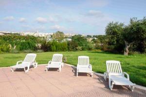 eine Gruppe von vier weißen Stühlen auf einer Terrasse in der Unterkunft Villa Montedoro Luxury in Noci