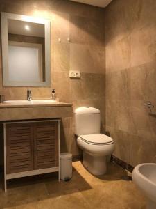 een badkamer met een toilet, een wastafel en een spiegel bij Ground floor 2 bed apartment with 5 pools and large terrace in Manilva