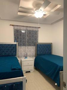 - une chambre avec 2 lits avec des draps bleus et une fenêtre dans l'établissement Hermoso residencial con piscina,seguridad 24 horas, à Santiago de los Caballeros