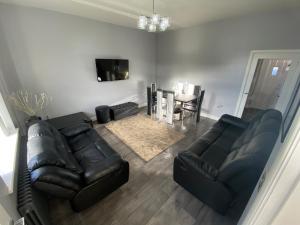 a living room with black leather furniture and a table at Entire Holiday Home in Mirfield